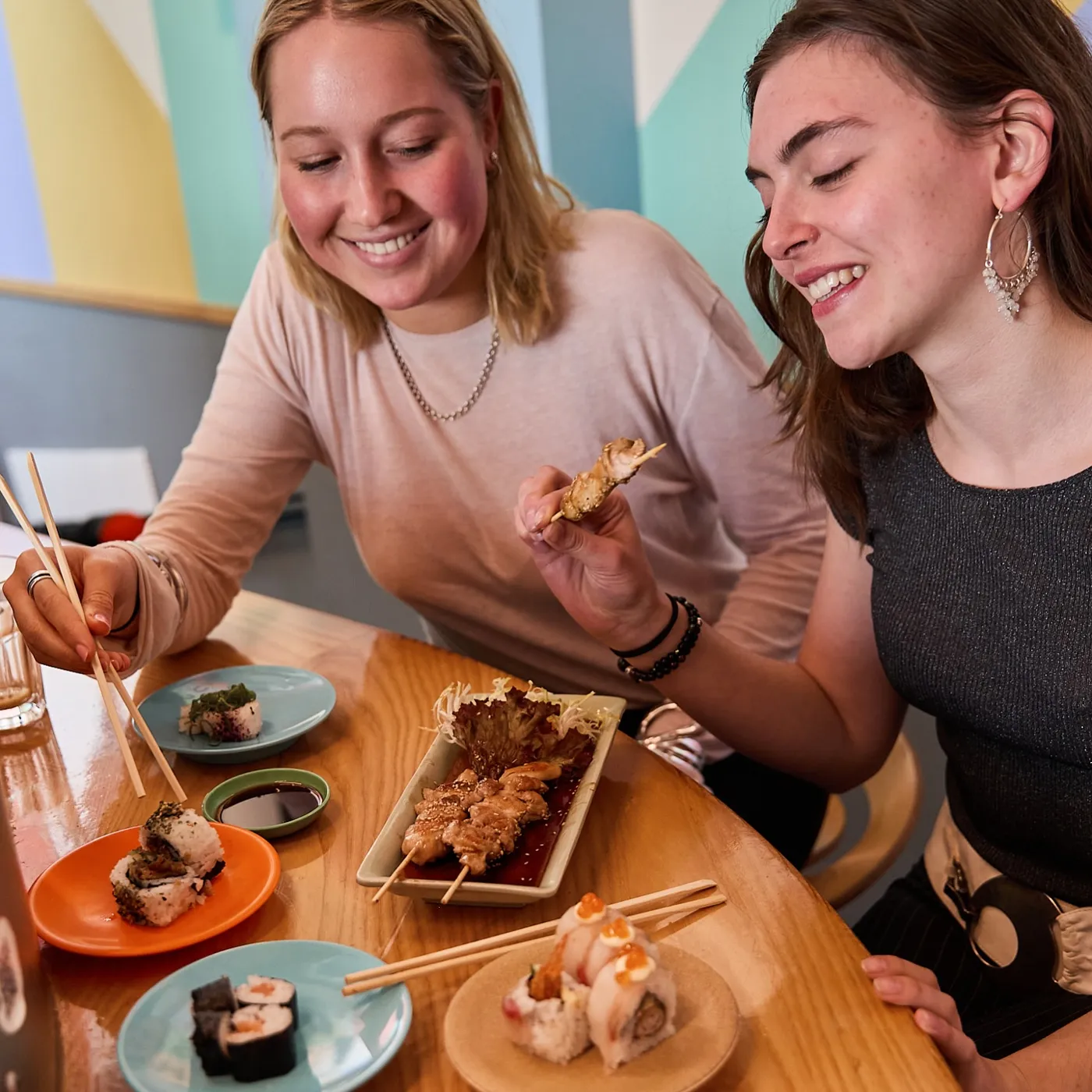 Twee vriendinnen lachen om spiesjes en sushi