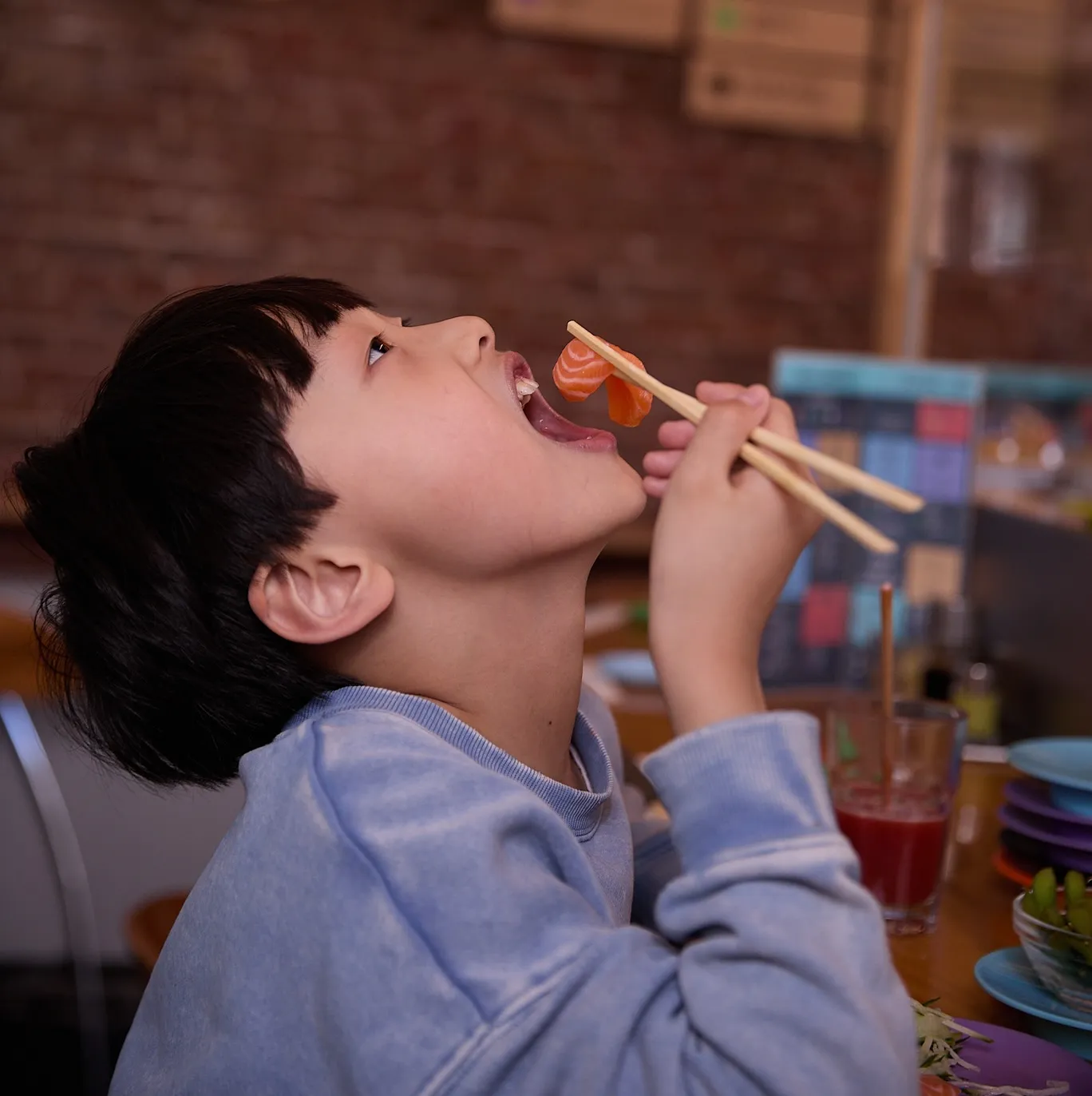 Een jongen neemt een grote hap sushi